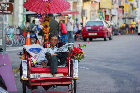 GEORGETOWN, MALAYSIA - JANUARY 19  Trishaw driver waiting for a customers on the street on January 19, 2014 in Georgetown, Malaysia  The trishaw ride is a famous attraction for tourists to see the city of Georgetown のeditorial素材