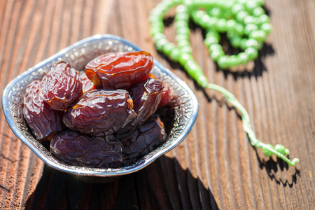 Beautiful bowl full of date fruits symbolizes Ramadan (Holy month of Muslims). On a wooden tableの写真素材