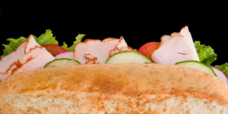Fresh roasted turkey/chicken sandwich with lettuce, cucumbers and tomatoes isolated on black