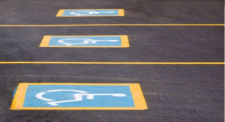Row of parking spaces with a handicapped signの写真素材