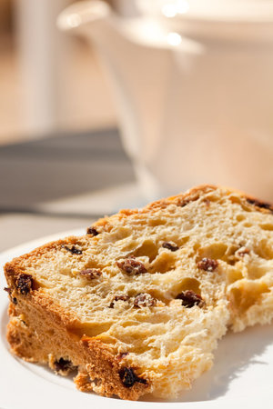 A slice of fruitcake served with tea on a patio - close view