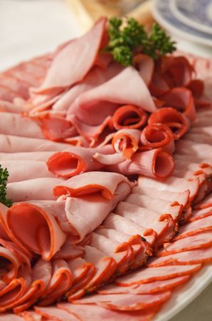 Assorted sliced ham, sausage and turkey arranged on a plateの写真素材
