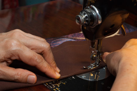old woman hand using sewing machine