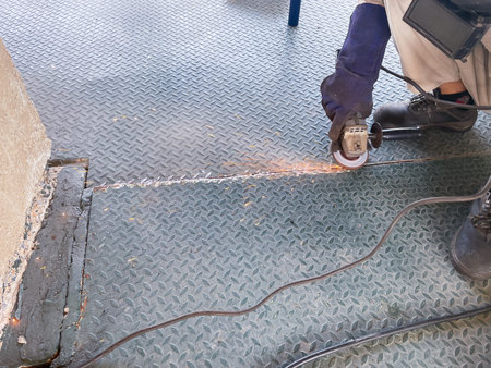 Worker cutting metal with angle grinder in a construction site.