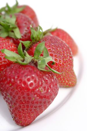 Six juicy strawberries on a white plate, view from above with focus on middle strawberry, portrait formatの写真素材