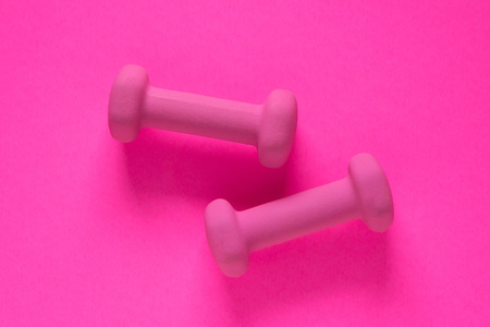 Fitness equipment with womens pink weights/ dumbbells isolated on a pink background with copyspace (aka empty text space).の写真素材