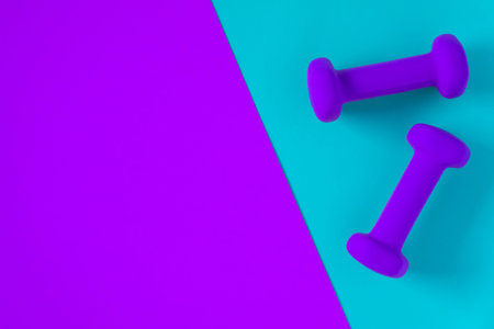Fitness equipment with womens purple weights/ dumbbells isolated on a light sky blue and purple...