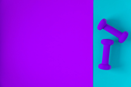 Fitness equipment with womens purple weights/ dumbbells isolated on a light sky blue and purple background with copyspace (aka empty text space).の写真素材