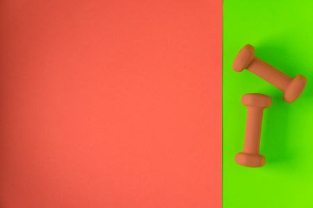Fitness equipment with womens yellow orange weights/ dumbbells isolated on a neon lime green and orange background with copyspace (aka empty text space).の写真素材