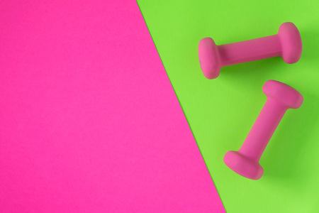 Fitness equipment with womens pink weights/ dumbbells isolated on a lime green and hot pink background with copyspace (aka empty text space).の写真素材