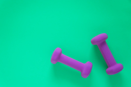 Fitness equipment with womens purple weights/ dumbbells isolated on a teal green background with copyspace (aka empty text space).の写真素材