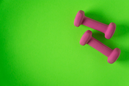 Fitness equipment with womens pink weights/ dumbbells isolated on a lime green background with copyspace (aka empty text space).の写真素材