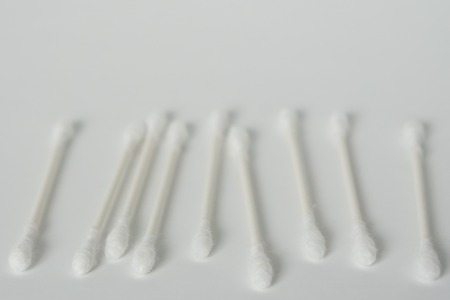 Q tip, or cotton bud swab top view on horizontal white background with blank empty space for copy or text; Features best health care hygiene practices to clean ear.の写真素材