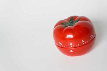 Close up view of mechanical tomato shaped kitchen clock timer for cooking and studying. Used for pomodoro technique for time and productivity management. Isolated on white background, at 0 minutes.の写真素材