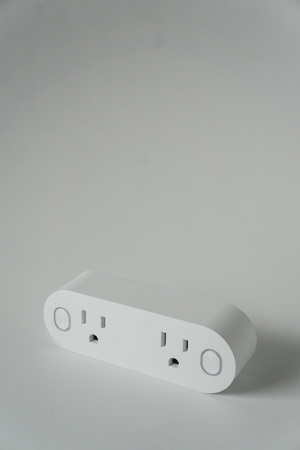 This double smart WIFI plug outlet can switch an electric device on or off via wi-fi. Isolated on a vertical white background with copyspace or empty room space for text or copy.の写真素材