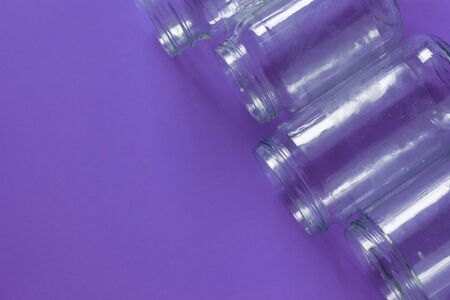 4 several glass jars on an isolated purple background with copyspace or blank empty room space for text or copy. Flat lay concept.の写真素材