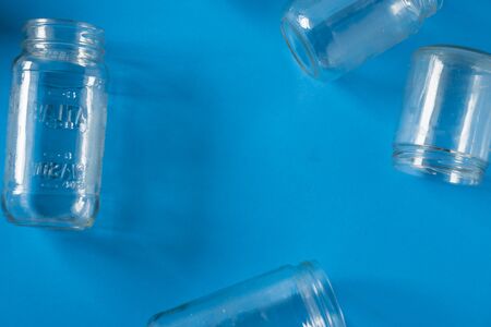 Isolated open glass jars laid flat on blue background - blank empty room space room for text, copy, or center copyspace. Recycling program or campaign image with an assortment of top view containers.の写真素材