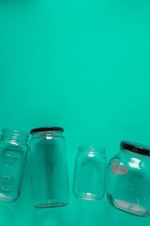 Isolated glass jars, flat on teal mint green background, blank empty room space room for text, copy, or copy space on top. Recycling program or campaign image with an assortment of top view containersの写真素材