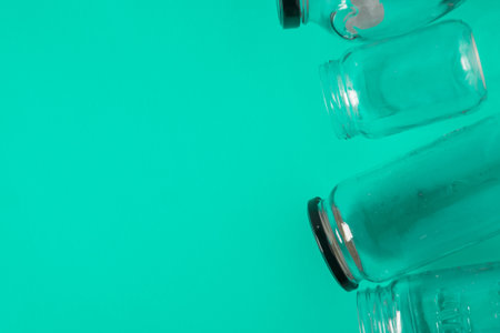 Isolated glass jars laid flat on teal mint green background, blank empty room space room for text,...
