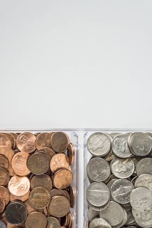 Isolated organized loose coin change on bottom side, white background, blank empty room space for copy or text on top. Financial organization money concept, top view of pennies, nickels, and quarters.の写真素材