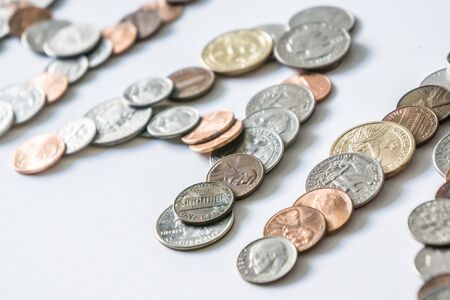 Coins isolated on solid white background spelling the word Money from loose coin change. Blank empty room space for text or copy. Financial mockup concept on flat lay backdrop with unique lettering.の写真素材