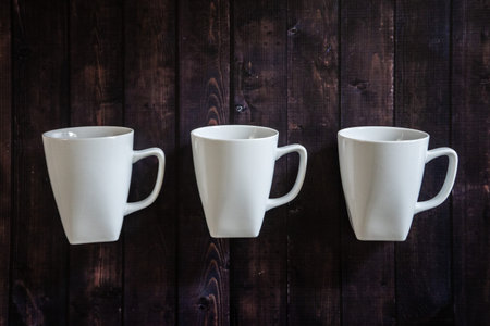 3 coffee mugs on a wooden table background - morning espresso java pick me up drink. Three cups of...