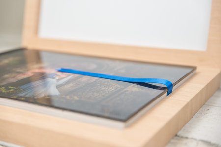 Close up side view of blue ribbon in a tan wooden wedding album box. Blank empty room space for text...