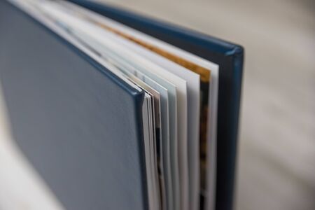 Side view close up of thick and rigid wedding album pages in a book with navy blue leather cover. Blank empty room space for text or copy.の写真素材