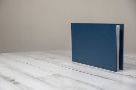 Navy blue leather wedding photography album book - blank cover on isolated white wooden background...
