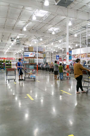 Kennesaw, GA / USA - 04/05/20: Masked people waiting in line at checkout practicing social distancing standing 6 feet apart via lines on ground at Costco store during Covid-19 Corona Virus Pandemic.のeditorial素材