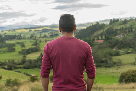 Man on the top of a mountain with his backs looking on horizon.の写真素材