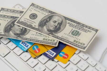 Online Commerce, Ecommerce, credit and debit cards with dollars and a keyboard.のeditorial素材