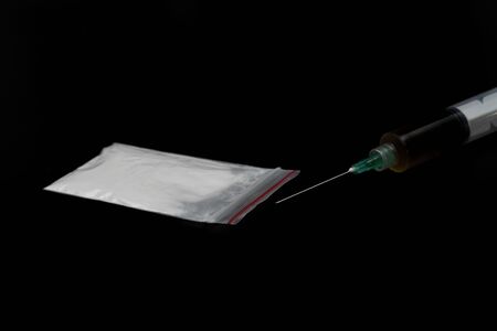 Cocaine or other illegal drugs, white powder, syringe, isolated on black glossy backgroundの写真素材