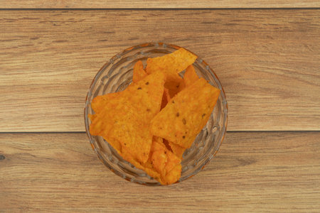 Plate with tasty nachos with wooden background