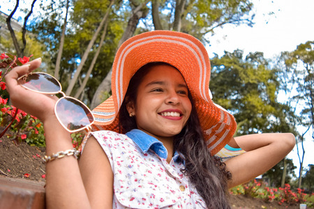 Young, beautiful and impressive, this is how this beautiful Latina looks with her wide smile contemplating all her suitors to whom she has arrows. She wears a dress, a sun hat and sunglasses.の写真素材