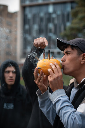 BogotÃ¡, Colombia - April 20th, 2022: young man smoking marijuana from a papaya