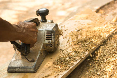 Hands of a carpenter planing woodの写真素材