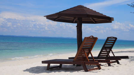 Beach chairs with umbrella and beautiful white sand beach. Panorama of tropical beach with white sand and turquoise water. Travel summer holiday background conceptの写真素材