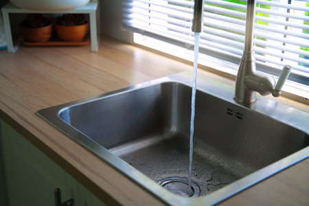 Water running from the tap into a kitchen sink. Clean and drinking water. Save water and...