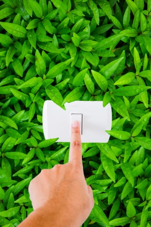 finger pointing at switch with leaf background - save energy concept の写真素材