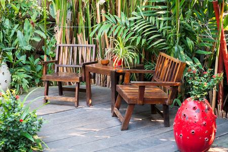 wooden chairs in a garden with tropical leaves in the backgroundの写真素材