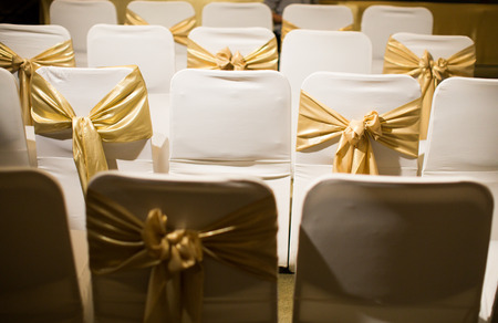 Wedding chairs decorated with golden ribbon in warm atmosphereの写真素材