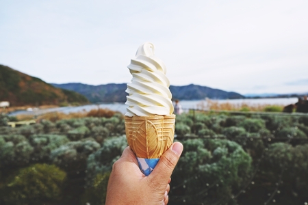 hand holding vanilla soft ice cream with mountain backgroundの写真素材