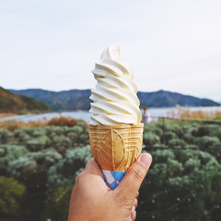 hand holding vanilla soft ice cream with mountain backgroundの写真素材