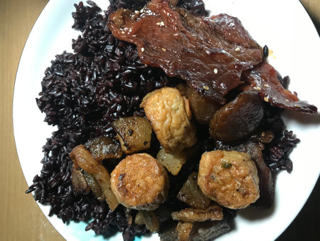 Rice with meat and vegetables on a white plateの写真素材