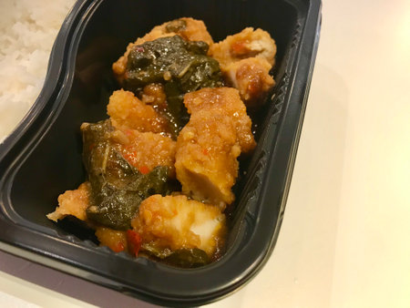 Fried pork with sweet and sour sauce in black plastic box.の写真素材