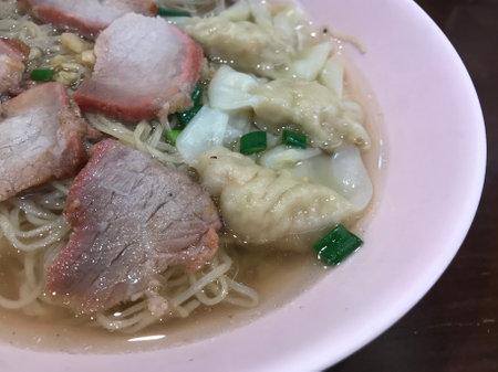 Noodle soup with pork and vegetable in pink bowl.の写真素材