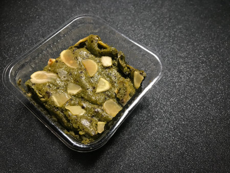 Pistachio sauce in plastic container on black background. Toned.の写真素材