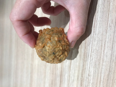 Fried fish ball in hand on wooden background. Top view.の写真素材