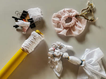 Shibori, White cotton fabric tied with elastic rubber and rolled over the yellow pipe on the white floor. Difference tie-dye methods. Preparing to tie-dye.の写真素材